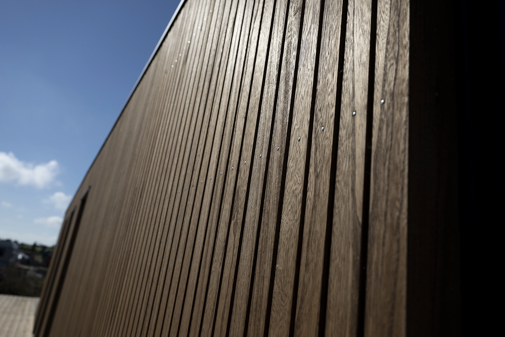 Knastfri kiri-facade i sollys Knastfri facade i kiri-træ med lodret profil og skarpe linjer i sollys